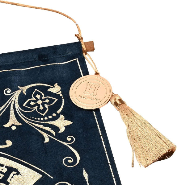 Decorative book with gold tassel and 'Hogwarts' emblem on a white background