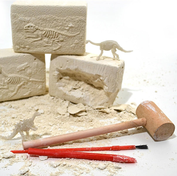 Dinosaur excavation kit with blocks, tools, and small dinosaurs on a white background