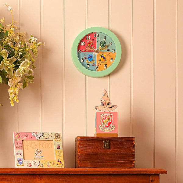 Colorful wall clock on a wooden shelf with decorative items against a beige wall.