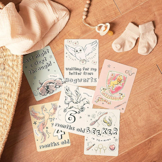Set of baby milestone cards on a wooden surface with socks and a basket.