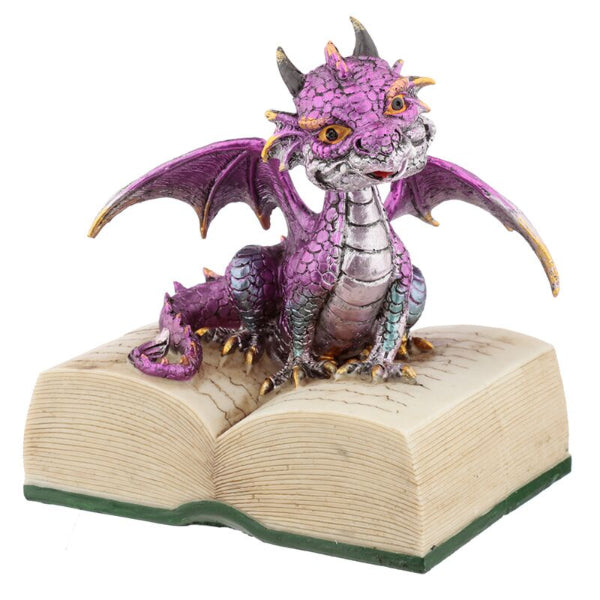 Purple dragon figurine on an open book with a white background