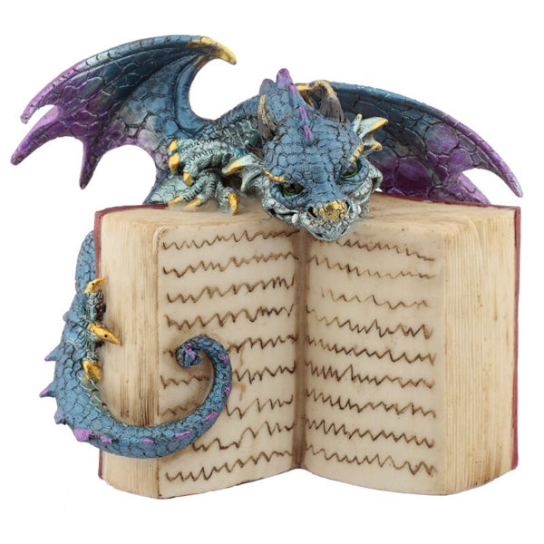 Dragon figurine perched on an open book with detailed wings and scales.