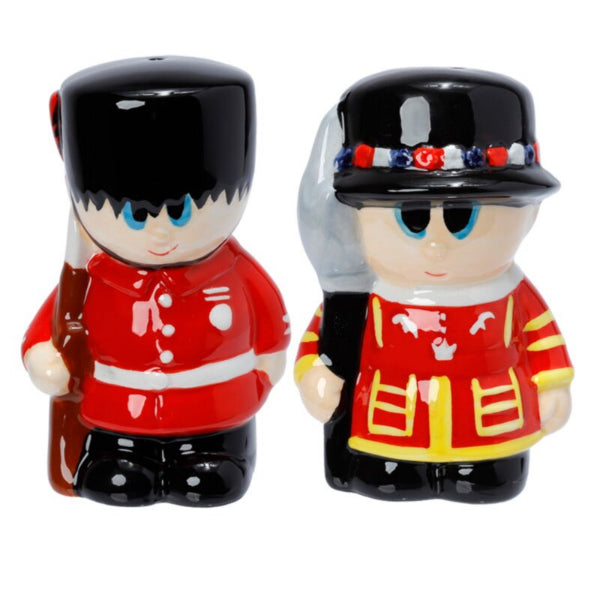 Two ceramic figures of British guards in red uniforms with black hats on a white background