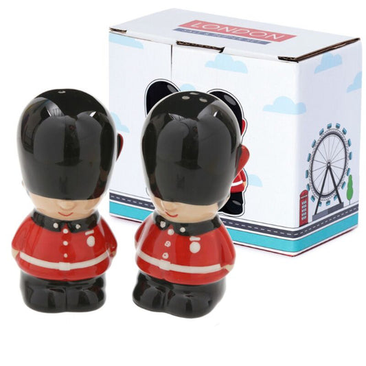 Two ceramic figures of British guards in red uniforms with a 'London' themed box in the background.