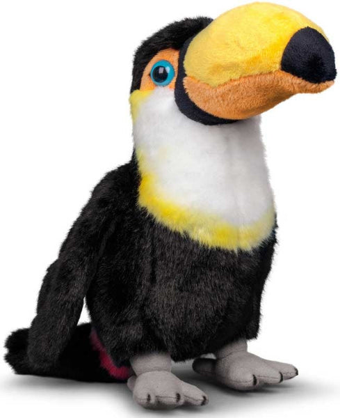 A plush toy toucan sitting upright on a white background. The toy features black fur on its body, a white chest, a bright yellow throat, a large yellow and orange beak, blue eyes, and gray feet.