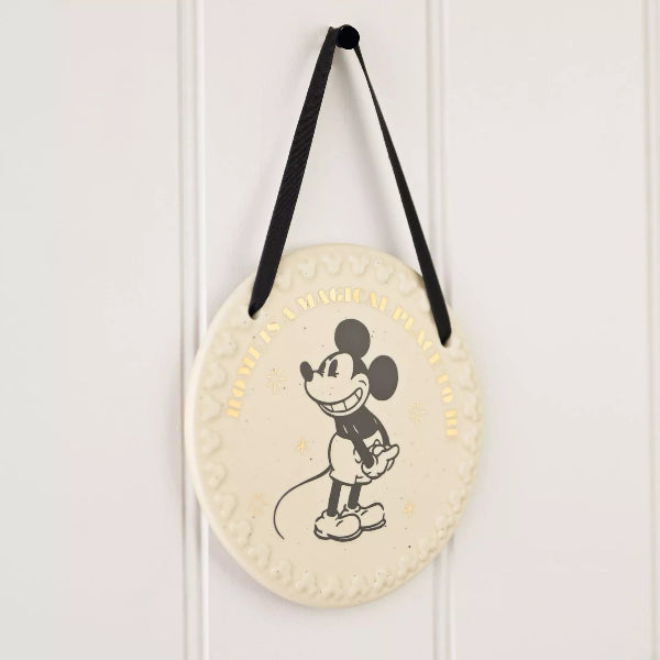Round decorative item with a cartoon character hanging on a white wall.