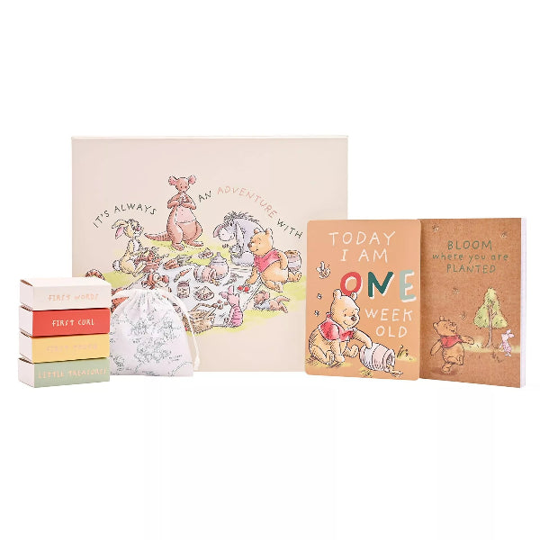 Collection of baby items including a book and cards with Winnie the Pooh illustrations on a white background.