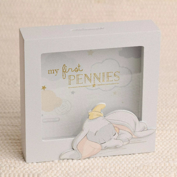 Children's piggy bank with Dumbo design and 'my first pennies' text on a beige background