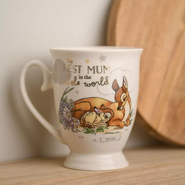 Mug with cartoon characters and text 'The Best Mum in the Whole World' on a wooden surface.