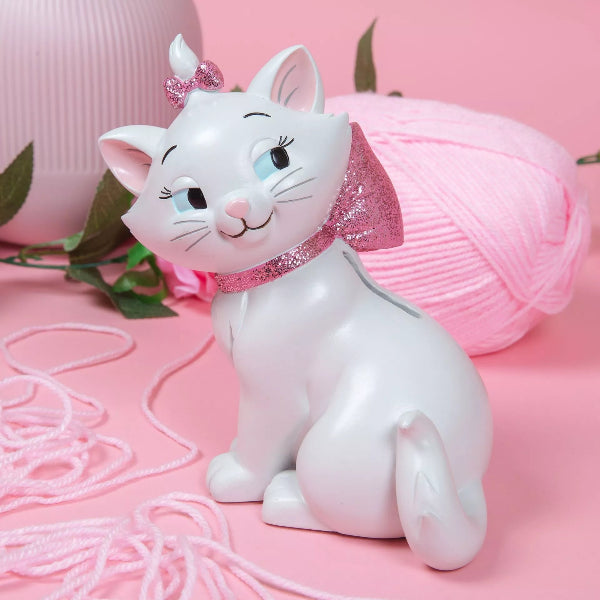White cat figurine with pink bow on a pink background