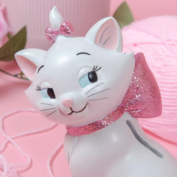 White cat figurine with pink bow and tail on a pink background