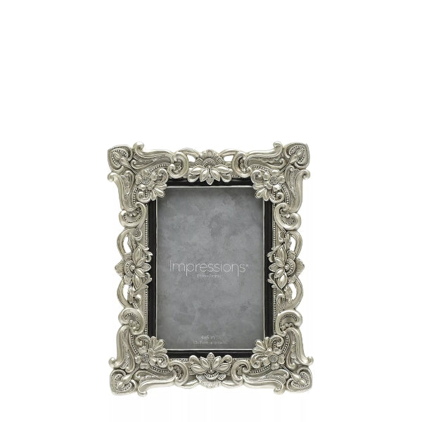 Decorative silver photo frame with intricate designs on a white background