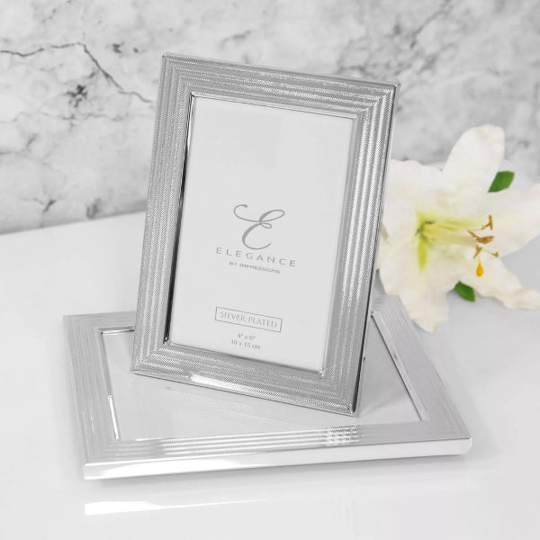 Silver photo frame with 'Elegance' branding on a marble surface with a white flower
