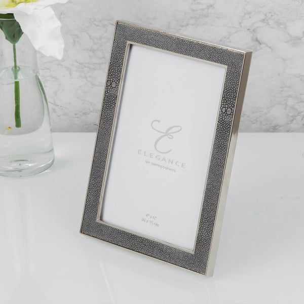 Silver photo frame with 'Elegance' branding on a white surface with a marble background