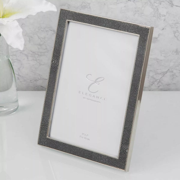 Silver photo frame with 'Elegance' branding on a white surface.