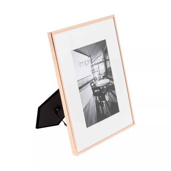 Rose gold photo frame with a black and white photo inside on a white background