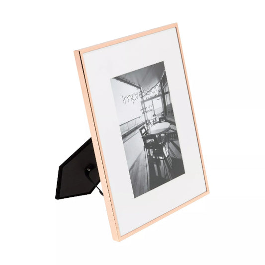 Rose gold photo frame with a black and white photo inside on a white background