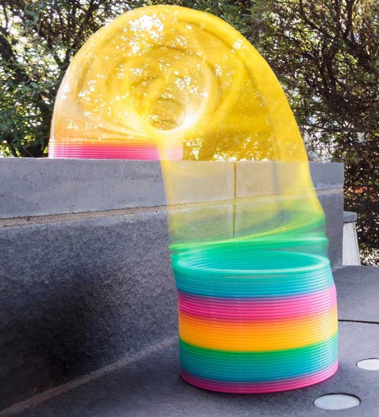 Stack of colorful plastic buckets with a transparent yellow lid on a concrete surface.