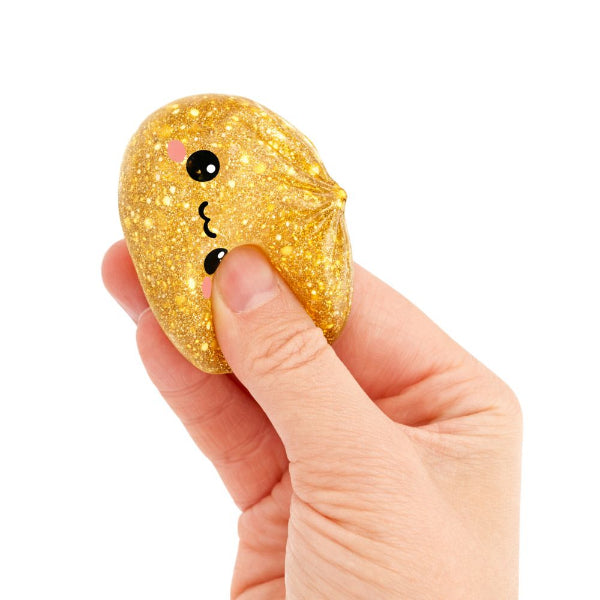 Gold glittery stress ball with a face on a white background