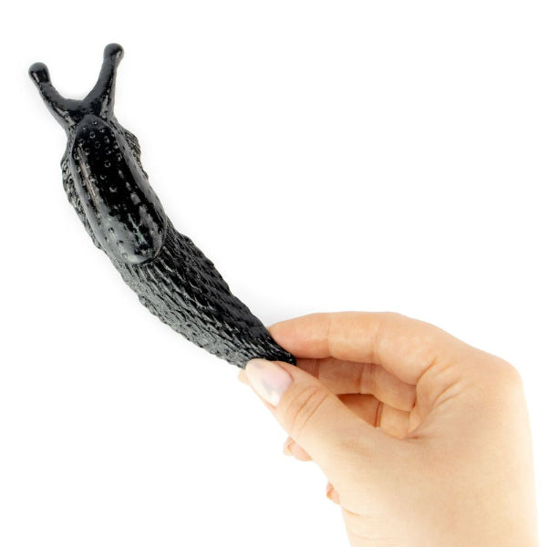 Hand holding a black slug-shaped object against a white background
