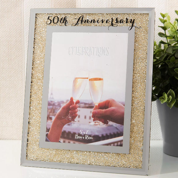 50th Anniversary celebration frame with a photo of two hands holding glasses.